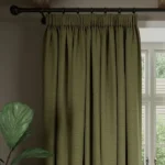 Pleated olive green soundproof curtain hangs on rod.