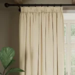 beige soundproof curtain hangs on rod.