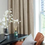 taupe soundproof curtain, plant, and diffuser.